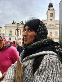 Young woman smiling while standing in city against sky