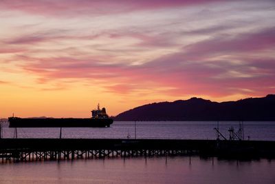 Silhouette pier over sea against sky during sunset