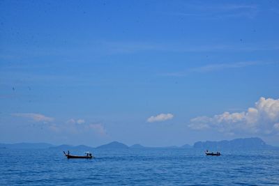 Boats sailing in sea against blue sky