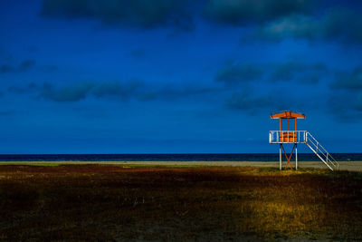 Lifeguard hut on beach against sky during sunset