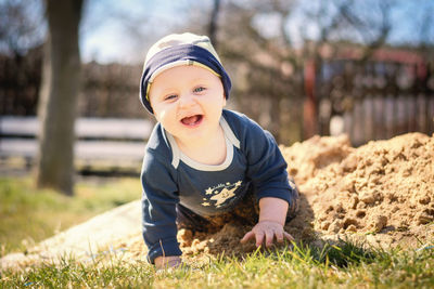 Portrait of cute cheerful baby boy kneeling on land