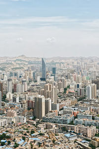 Aerial view of city buildings against cloudy sky