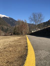 Road amidst bare trees against sky