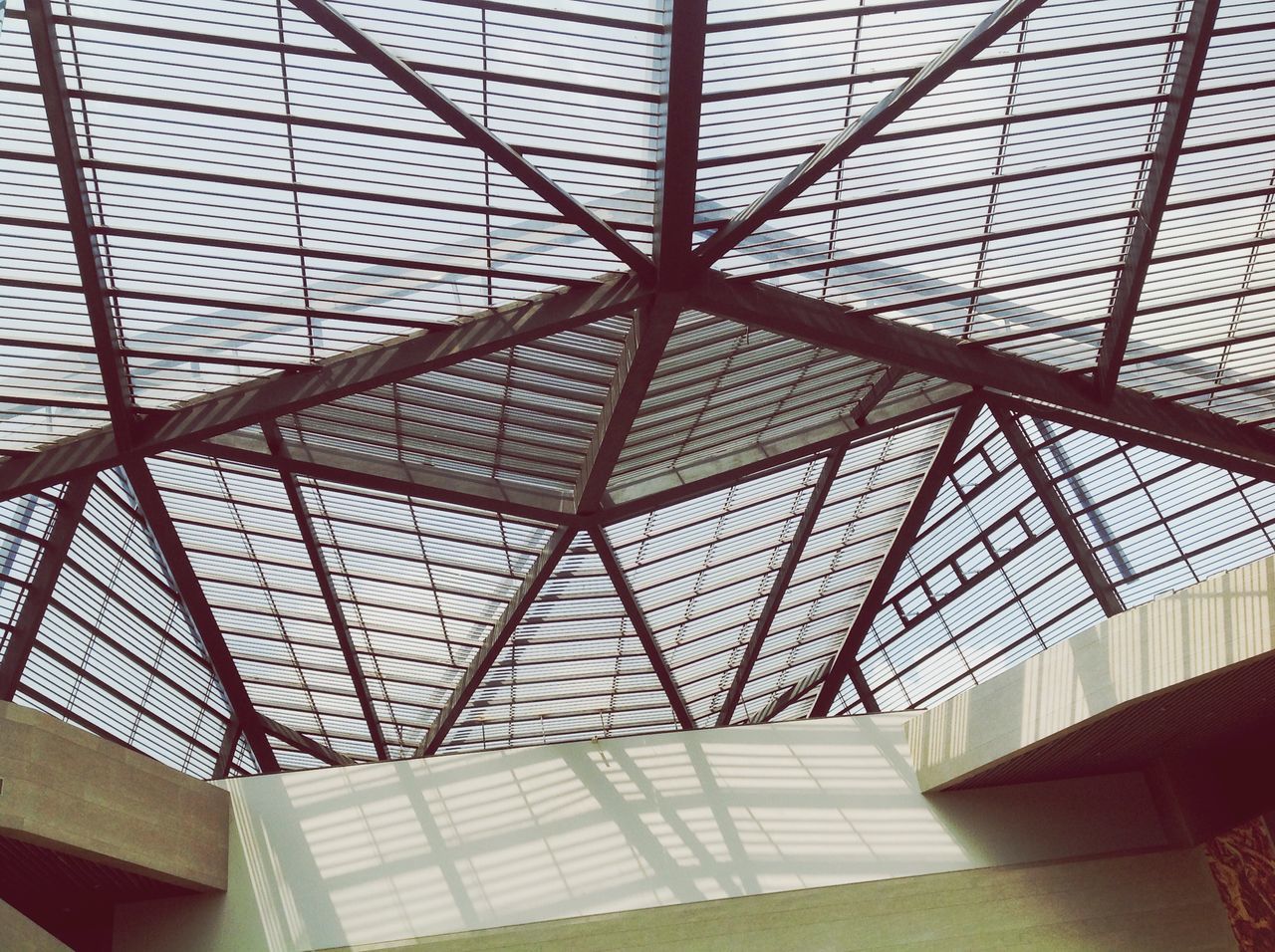 indoors, architecture, ceiling, built structure, pattern, low angle view, glass - material, full frame, design, architectural feature, skylight, backgrounds, modern, directly below, metal, geometric shape, grid, window, transparent, day