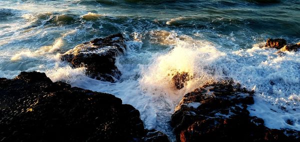 High angle view of waves splashing on rocks