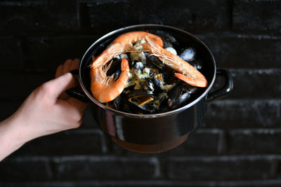 The mussels with sauce and shrimps on a black background