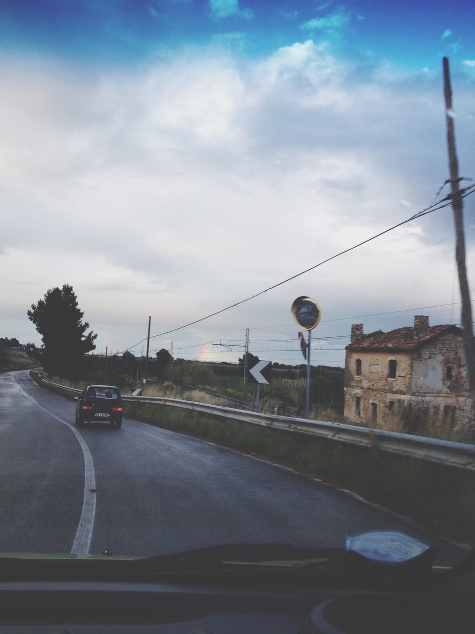 transportation, mode of transport, car, land vehicle, sky, architecture, built structure, building exterior, road, cloud - sky, street, city, bridge - man made structure, connection, street light, travel, cloud, outdoors, road marking, on the move