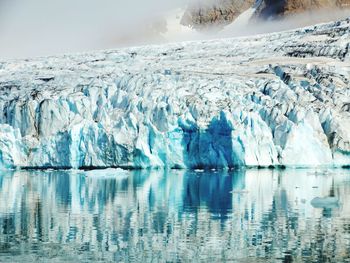 Reflection of glaciers on frozen lake