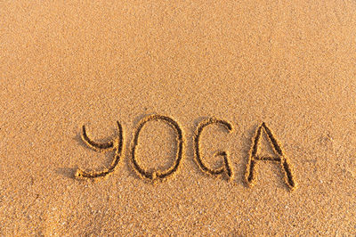 The inscription yoga on the sea sand. sea coast with yoga post with place for text