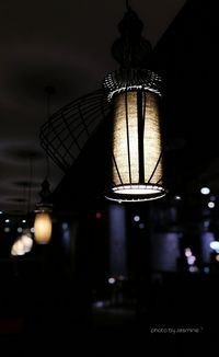 Low angle view of illuminated light bulb hanging at night