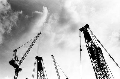 Low angle view of cranes at construction site against sky