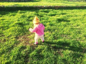 Rear view of baby girl standing on field