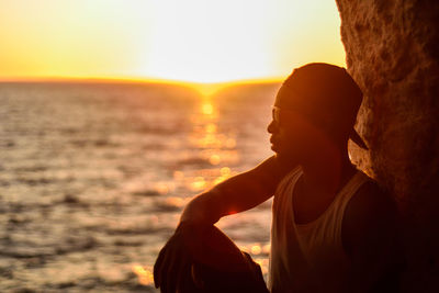 Side view of woman standing at beach during sunset