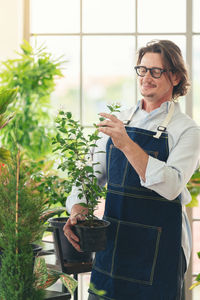 Man taking care of her potted plants at home, gardening, planting at home