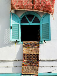 Handmade moroccan carpet hanging on the window of a carpet store in asilah