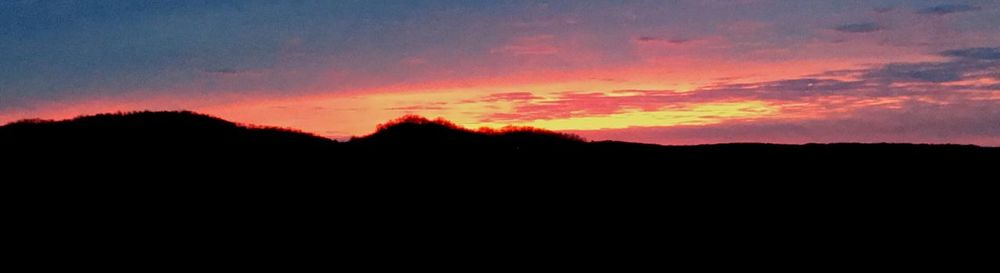 Scenic view of silhouette mountains against sky at sunset