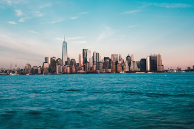 Sea and buildings in city against sky