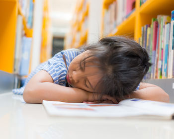 Girl with book sleeping in library