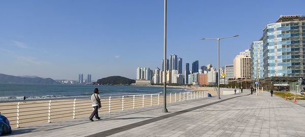 Man by sea against buildings in city