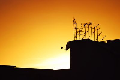 Low angle view of silhouette building against orange sky