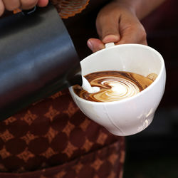 Midsection of man holding coffee cup