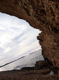 Rock formation on beach against sky