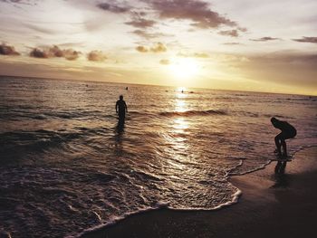Silhouette people standing on beach against sky during sunset