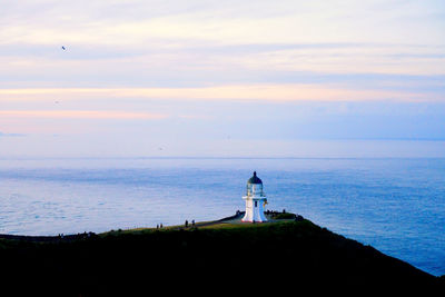 Lighthouse by sea against sky