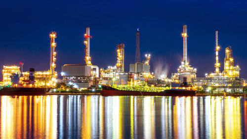 Illuminated factory against sky at night