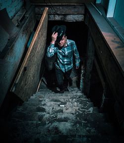 Portrait of man walking on steps while wearing hat at abandoned building
