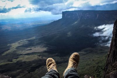 Low section of man on mountain against sky