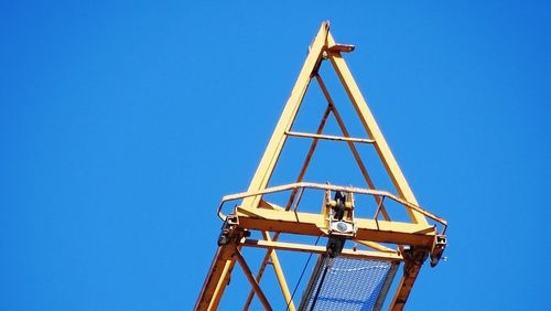 Low angle view of crane against clear blue sky