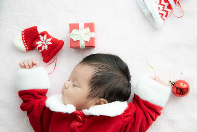 Directly above shot of baby girl wearing santa claus costume sleeping on bed at home