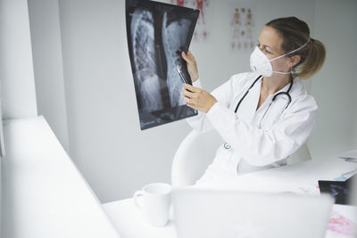 Smiling doctor holding medical x-ray at clinic