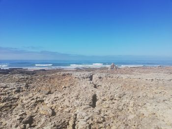 Scenic view of beach against clear blue sky