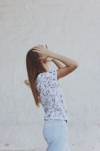 Side view of young woman standing by wall