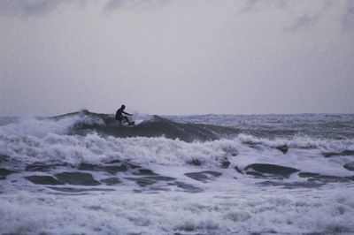 Man surfing in sea against sky