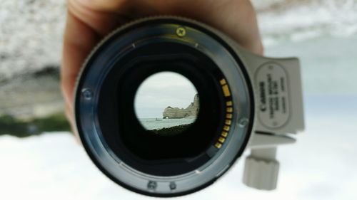 Cropped image of hand holding lens at riverbank