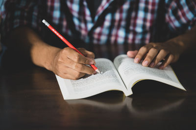 Midsection of man reading book on table