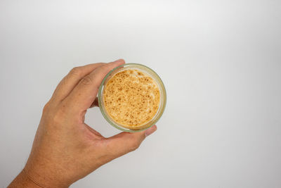 Cropped image of hand holding coffee cup against white background