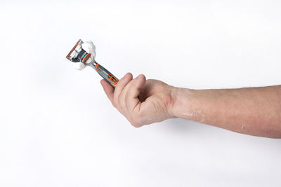 Midsection of man holding cigarette against white background