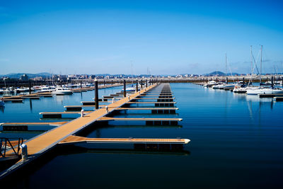 Boats moored in harbor against blue sky