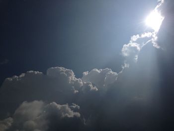 Low angle view of sun shining through clouds