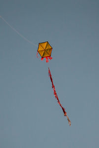 Low angle view of kites flying against clear blue sky