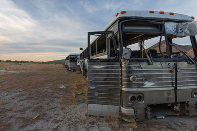 Abandoned vehicles on field against sky