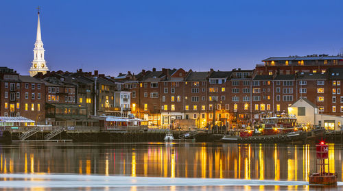 Illuminated buildings in city against clear sky