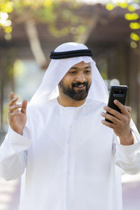 Man holding mobile phone standing outdoors