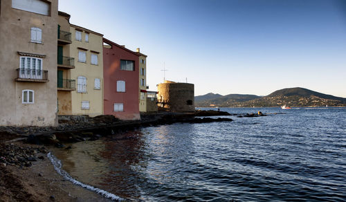 Houses by river against clear sky