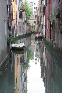 Boats moored in canal amidst city