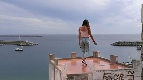 Rear view of young woman standing at observation point by sea